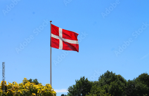 Red and white Danish flag in the blue sky on a sunny celebrations day in Denmark photo