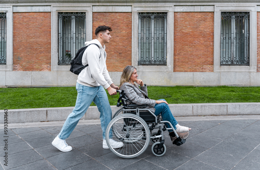 Teenager pushing her mother in a wheelchair down the street.