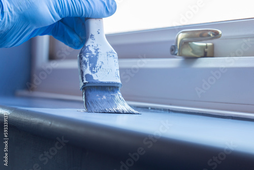 Cuadro en lienzo Person painting a window sill with blue paint using a brush