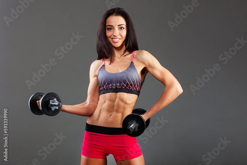 A beautiful young sports girl on a gray background, beautiful abdominal muscles, a beautiful figure.