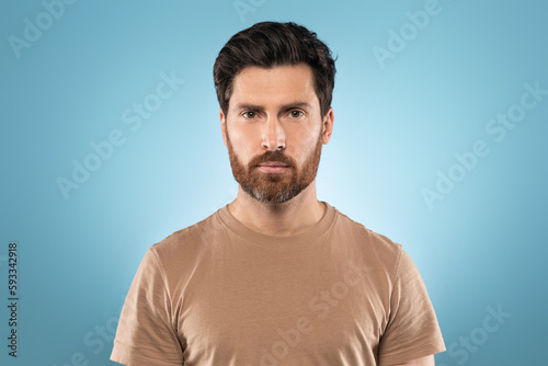 Portrait of handsome middle aged serious well-groomed brunet man posing isolated over blue color studio background