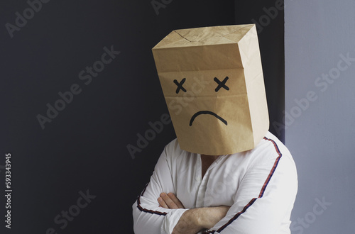 Sad man with a bag on his head, with a drawn crying emoticon. photo