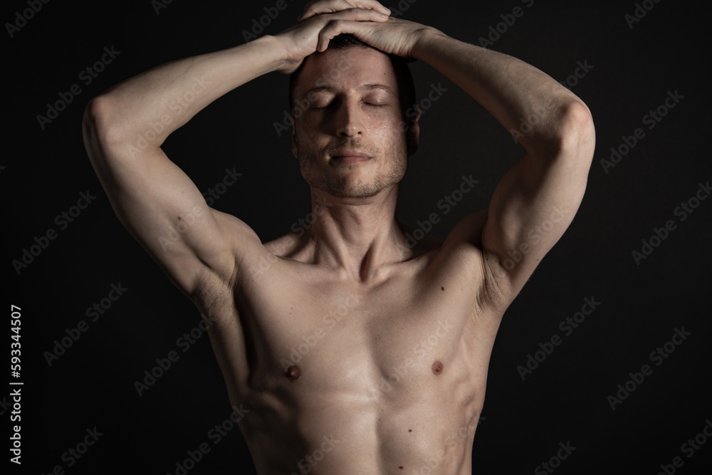 Adult attractive man with a beautiful body posing in the studio. Black background.	