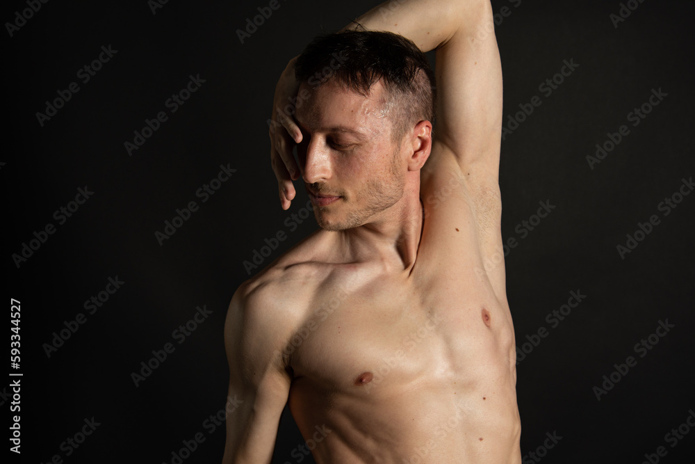 Adult attractive man with a beautiful body posing in the studio. Black background. Adult attractive man with a beautiful body posing in the studio. Black background.
