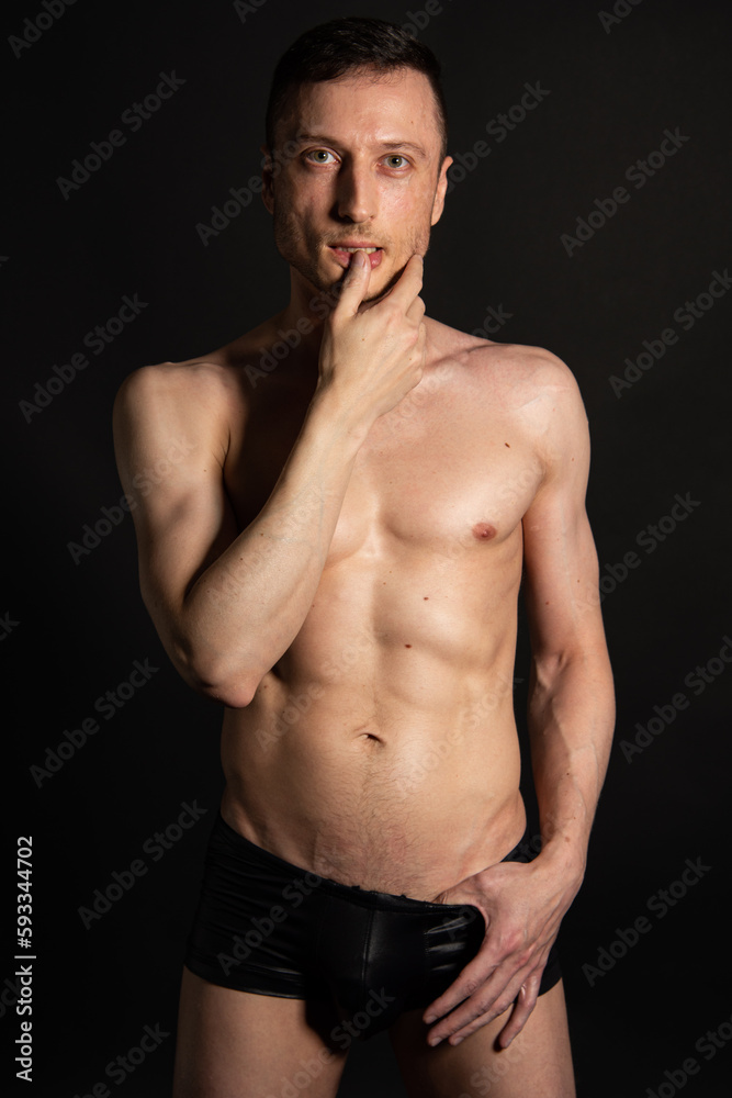 Adult attractive man with a beautiful body posing in the studio. Black background. Adult attractive man with a beautiful body posing in the studio. Black background.