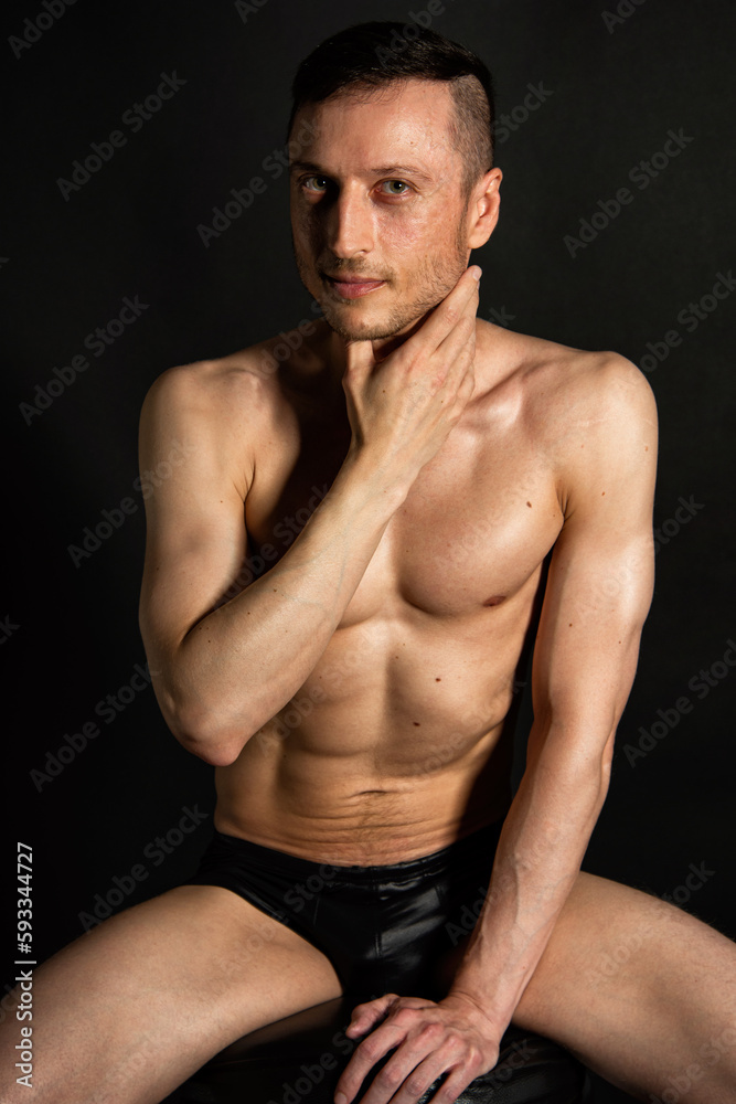 Fototapeta premium Adult attractive man with a beautiful body posing in the studio. Black background.