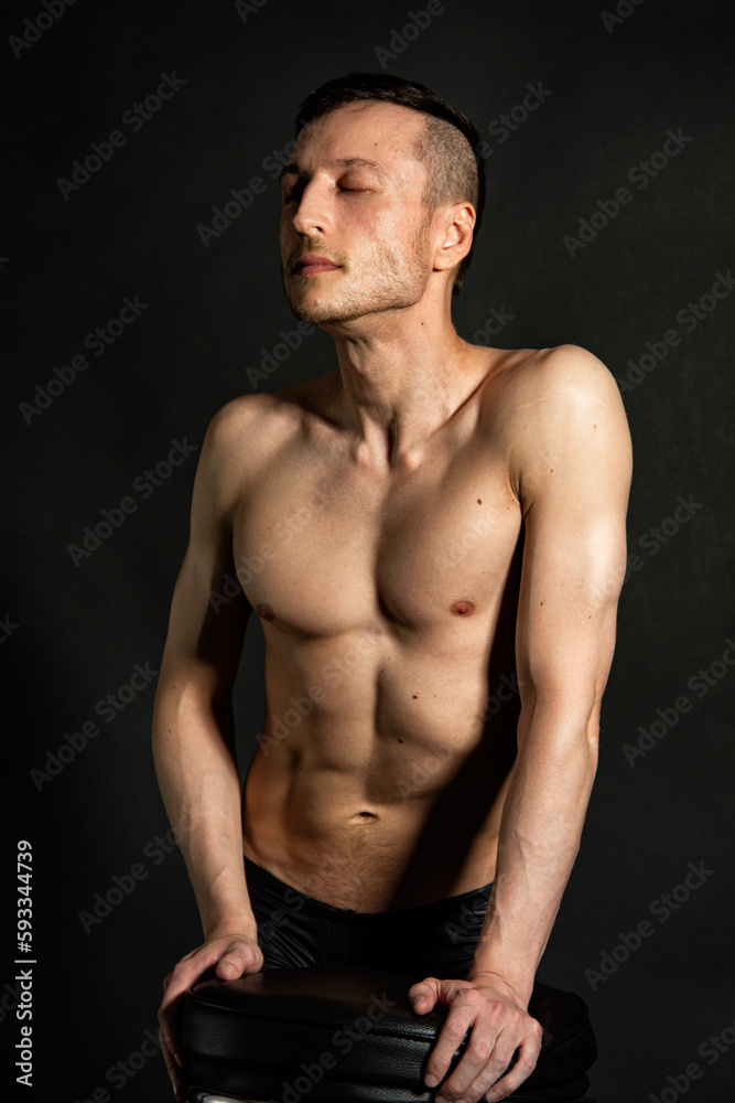Fototapeta premium Adult attractive man with a beautiful body posing in the studio. Black background. 