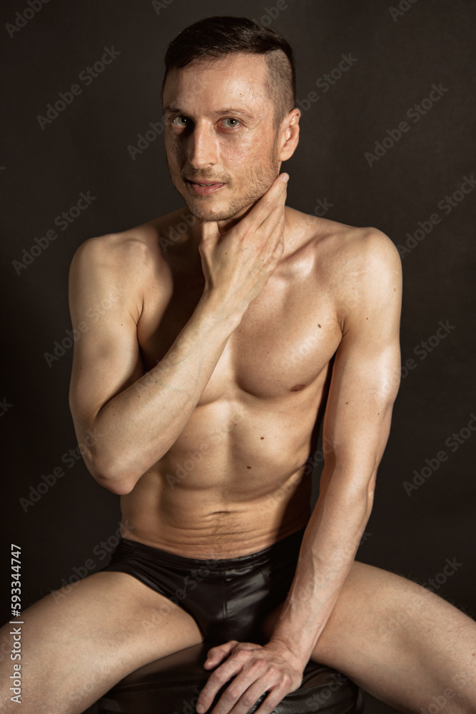 Fototapeta premium Adult attractive man with a beautiful body posing in the studio. Black background.
