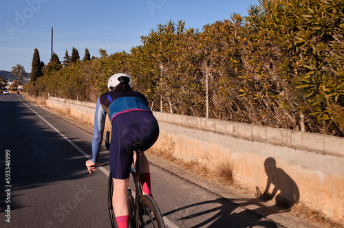 Male cyclist on time trial aero bike riding on empty road. Sport trainings approach that deliver results through hard work and dedication.Extremely strong motivated person. photo