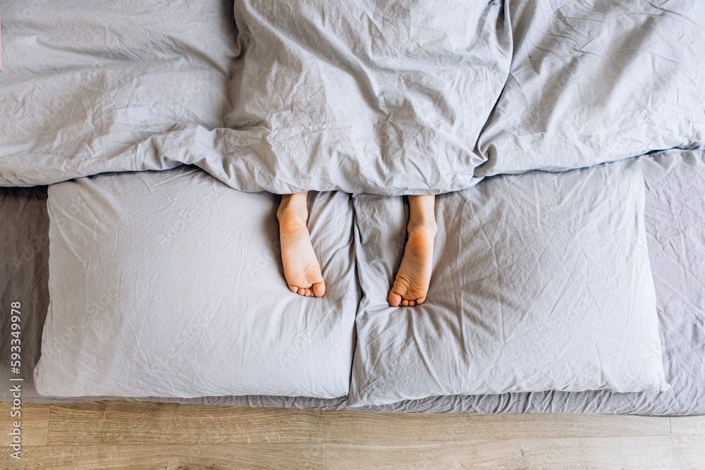 Kids child legs feet lying on pillows in bed at home. Child playing