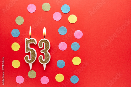 Number 53 on a red background with colored confetti. Happy birthday candles. The concept of celebrating a birthday, anniversary, important date, holiday. Copy space. banner
