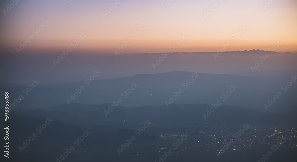 Panorama of mountain ranges at sunset and the city of Dogubayazit glows in the valley in the evening, minimalistic view from Mount Ararat