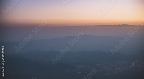 Panorama of mountain ranges at sunset and the city of Dogubayazit glows in the valley in the evening  minimalistic view from Mount Ararat