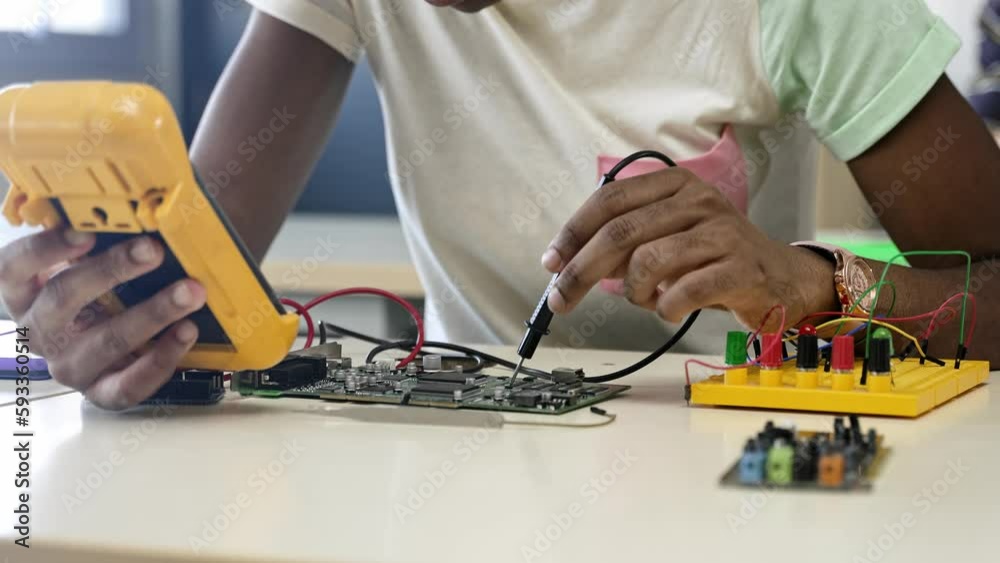 African student girl fixing circuit board with electrical tester in the engineering technology course