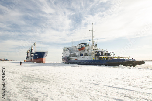 April, 2023 - Arkhangelsk. Dry cargo ship "Bering" and icebreaker "Captain Chaadaev". Icebreaking operations on the Northern Dvina River. Russia, Arkhangelsk region