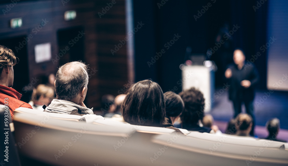 Speaker giving a talk in conference hall at business event. Rear view of unrecognizable people in audience at the conference hall. Business and entrepreneurship concept Speaker giving a talk in conference hall at business event. Rear view of unrecognizable people in audience at the conference hall. Business and entrepreneurship concept
