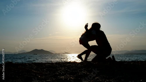 The father hugs the child. Silhouette of a happy dad hugging his daughter on the beach at sunset.