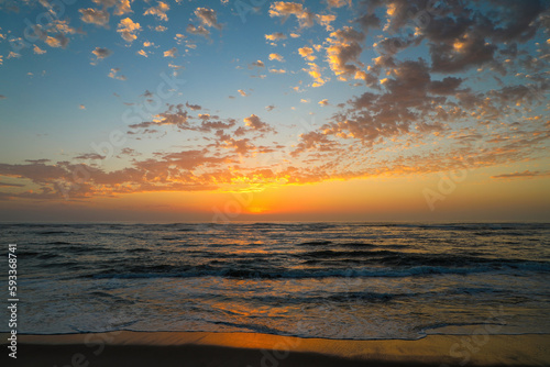 Bright orange beach sunset reflecting on the waves