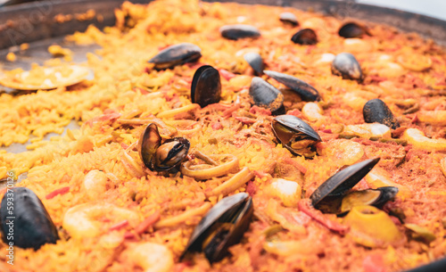 Kusząca hiszpańska paella z małżami, pełna smaku i kolorów. Wyrafinowane połączenie składników ukazuje bogactwo kuchni śródziemnomorskiej.