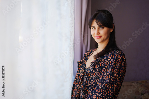 portrait of a beautiful young brunette woman in a dark dress in a home interior.