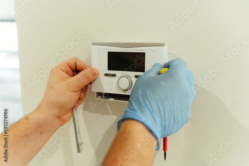electrician, male electrician repairs smart home with a screwdriver. electrical engineer installs and programs smart home.