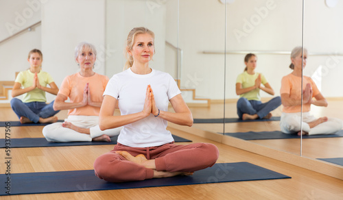 Portrait of middle age european female making yoga meditation in lotus pose in fitness studio