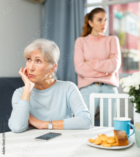 Mature woman and her daughter with smartphone resenting each other at home.
