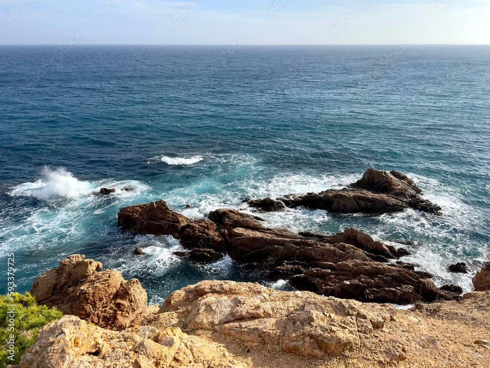 Mediterranean sea waves crashing on rocks in the water seen from a cliff, Costa Brava, Catalonia, Spain