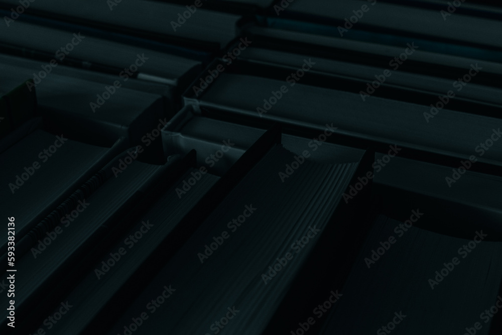 Obraz premium Deep dark background of books with black counterfoils and shady blue pages.