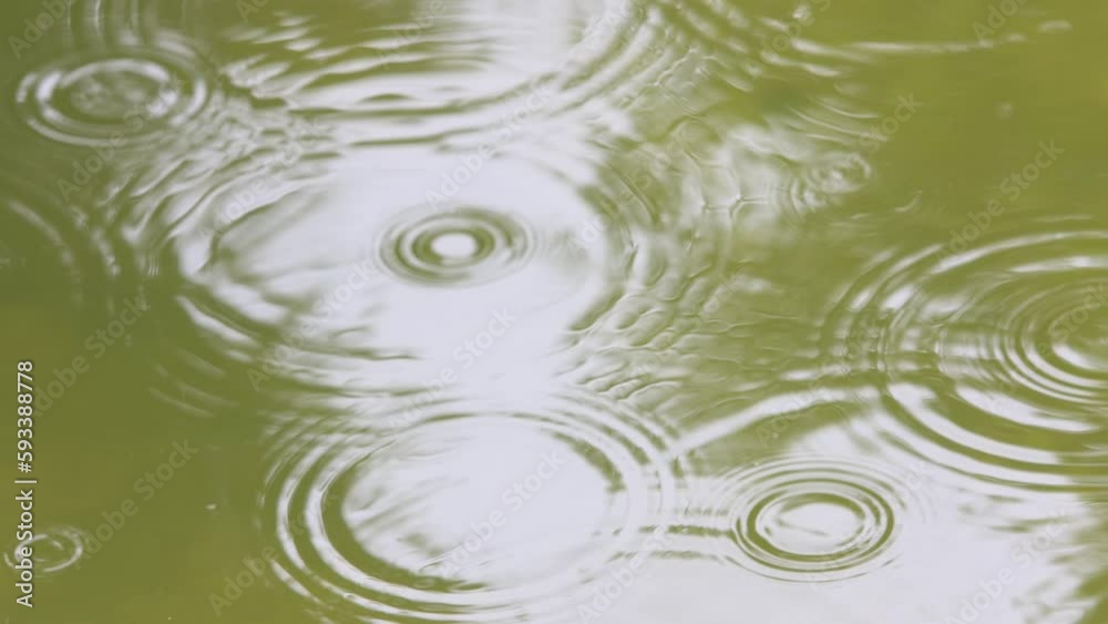 raindrops fall into the water,slow motion,raindrops create small waves on the water surface,