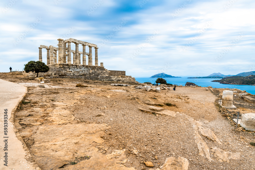 The ancient Poseidon Temple under dramatic cloudy skies in the hills of Cape Sounion on the Athenian Riviera near Athens Greece.
