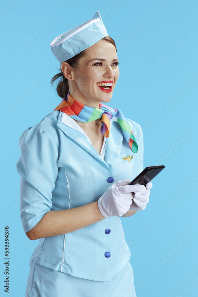 happy modern female air hostess on blue using smartphone happy modern female air hostess on blue using smartphone
