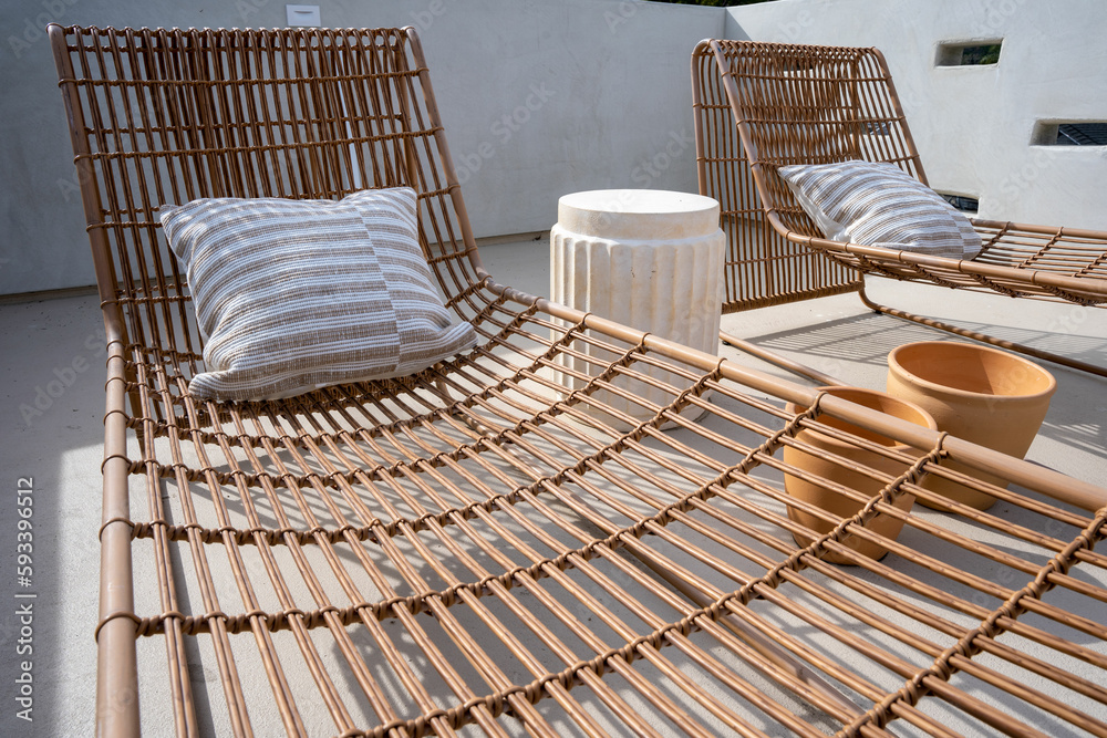 Two wicker sun lounge chairs on a roof top sun deck.
