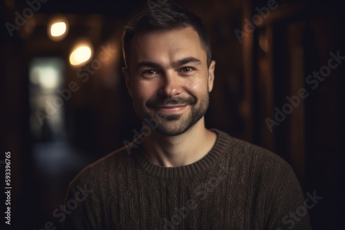 Portrait of a handsome young man in a dark room, looking at the camera.
