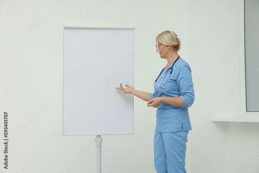 Professional doctor explaining something near flipchart indoors Professional doctor explaining something near flipchart indoors