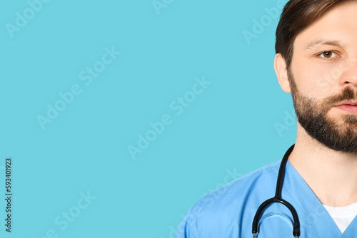 Doctor or medical assistant (male nurse) in uniform with stethoscope on turquoise background, closeup. Space for text photo