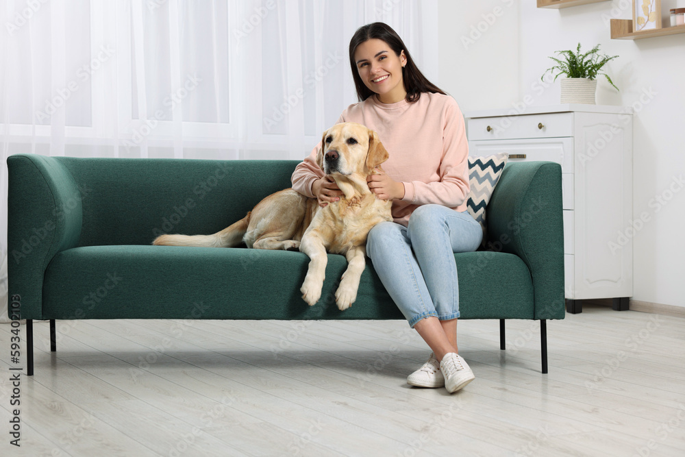 Happy woman with cute Labrador Retriever on sofa at home Happy woman with cute Labrador Retriever on sofa at home