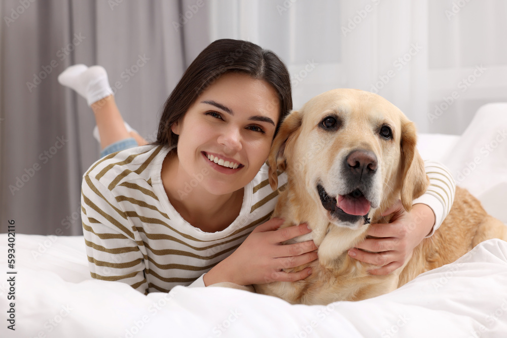 Happy woman with cute Labrador Retriever on bed at home Happy woman with cute Labrador Retriever on bed at home