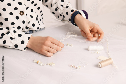 Dressmaker with sewing accessories at white table in atelier, closeup