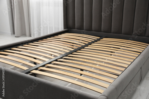 Modern bed with storage space for bedding under slatted base in room, closeup
