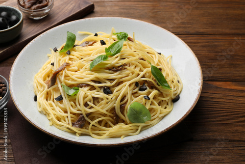 Delicious pasta with anchovies, olives and basil on wooden table