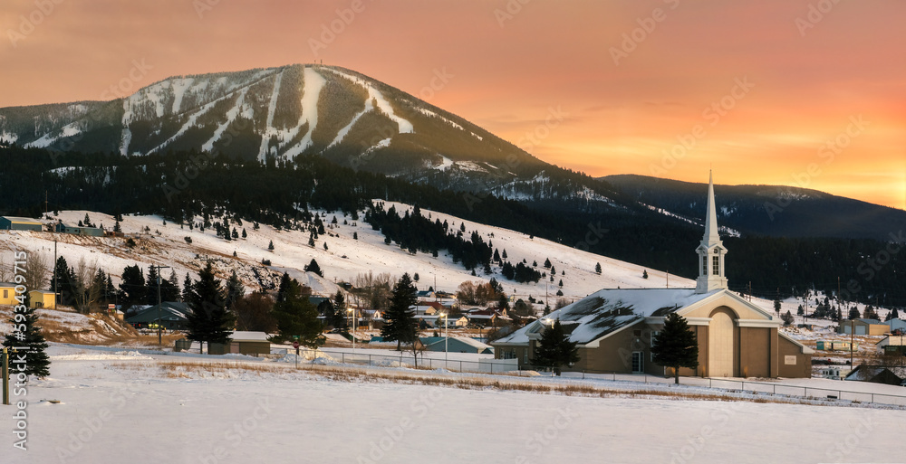 View of Discovery Ski area on Rumsey Mountain and Philipsburg community church in Philipsburg, Montana at sunset