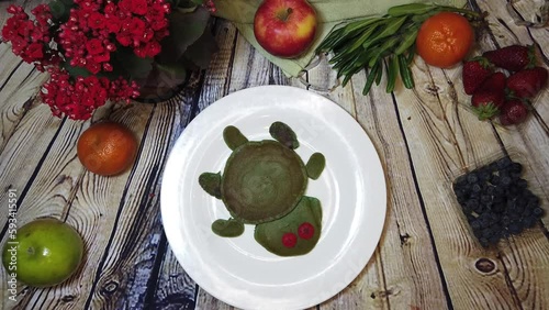 Plate with turtle pancake spins on the wooden table and dissapear. Stop motion flat lay. High quality 4k footage photo