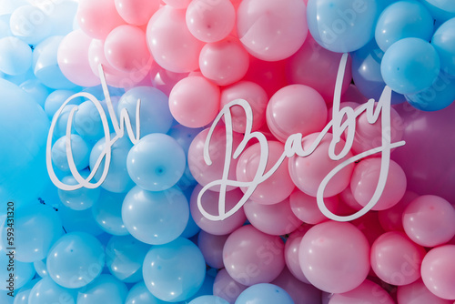 Background, wall with text oh baby. Photo zone, arch with pink and blue balloons for gender party. Boy or girl. Know gender of unborn child. Happiness of parenthood. Baby Shower party decor. Closeup. photo