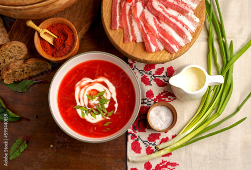 Traditional Ukrainian towel along with garlic, bread and salt. Traditional Ukrainian borsht, red vegetable soup or borscht with smetana on wooden background. Slavic dish with cabbage, beets, tomatoes 