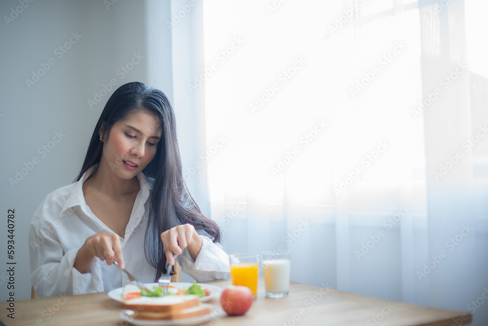 Beautiful asian woman is eagerly slicing a fried egg on a plate. Beautiful asian woman is eagerly slicing a fried egg on a plate.