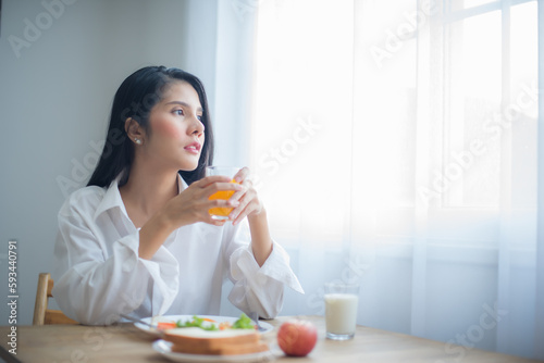 Beautiful asian woman eyes were fixed on the copy space and she held the glass of juice with a relaxed grip.