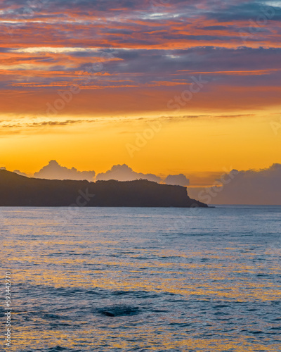 Sunrise and colourful high cloud over the sea and headland