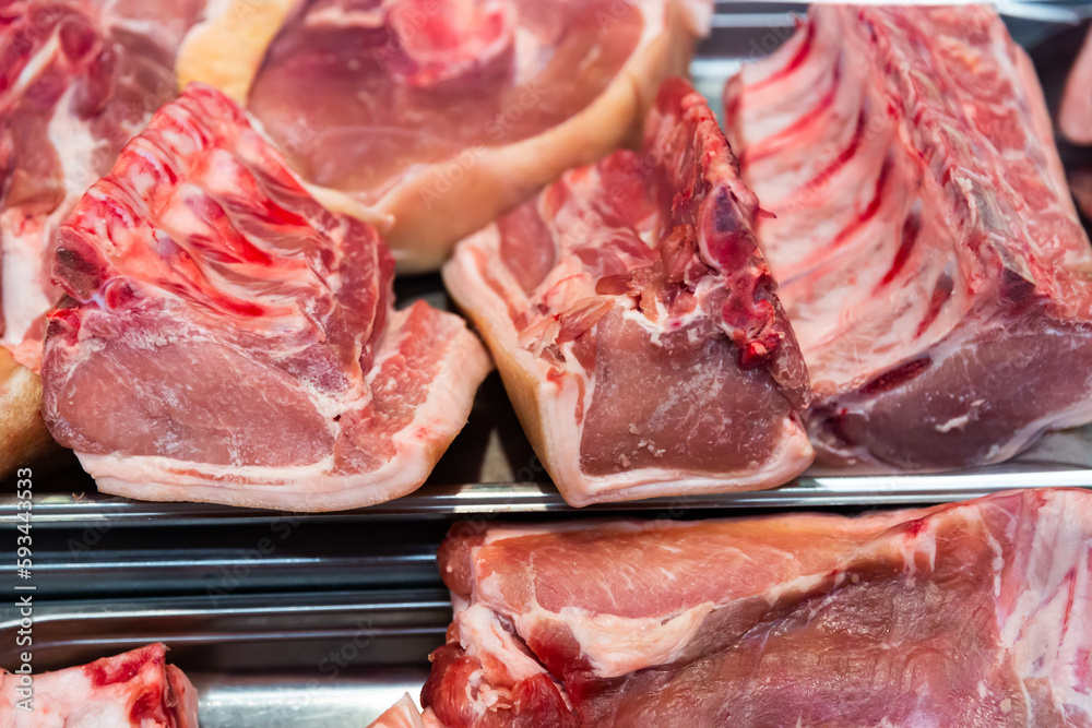Fresh slices of raw pork meat on counter in supermarket, nobody