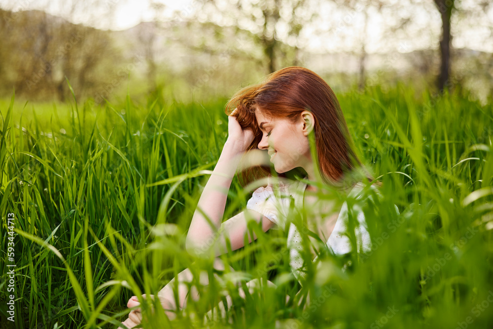 a young woman sitting resting in the tall grass straightening her hair a young woman sitting resting in the tall grass straightening her hair